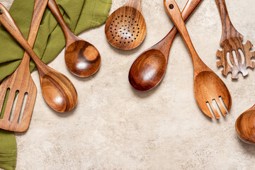 Various wooden kitchen utensils on a light concrete background top view. Copy space for text.