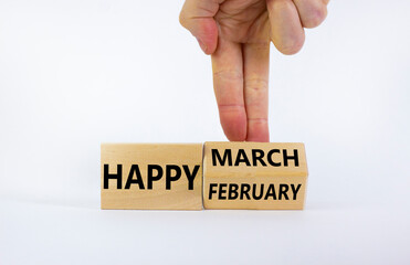 Symbol for the change from February to March. Businessman turns wooden cubes and changes words 'Happy February' to 'Happy March'. Beautiful white background, copy space. Happy March concept.