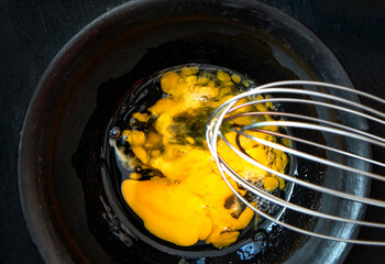 Beaten egg yolks in a bowl on a dark background
