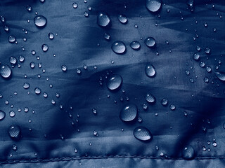 Water drops on waterproof membrane fabric. Detail view of texture of blue waterproof cloth.