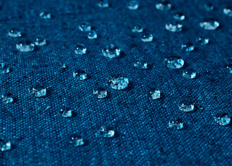 Water drops on blue waterproof fabric.