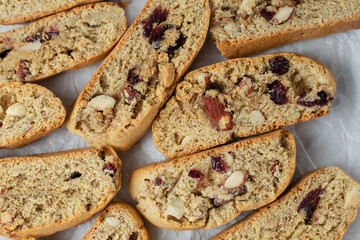 Italian biscotti cookies on baking paper. Top view fresh baked cookies with nuts and dried cranberries. Vegan recipe