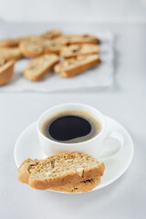 A cup of coffee with Italian biscotti cookie. Fresh baked cookie with white cup of coffee and blurred cookies. Vertical orientation