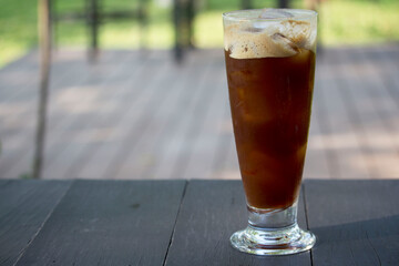 Iced coffee in a cup is placed on a beautiful wooden table.