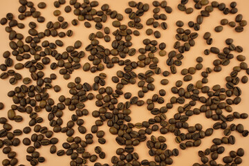 Roasted coffee beans on a beige background. Top view, copy space.