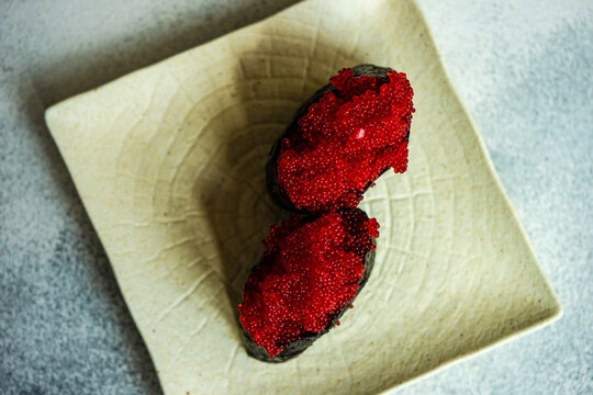 Overhead view of two tobiko nigiri sushi on a ceramic plate