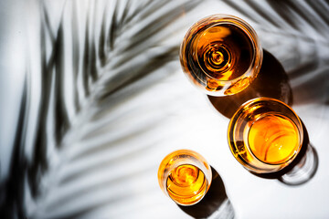 Hard strong alcoholic drinks, spirits and distillates in glasses: vodka, cognac, tequila, scotch, brandy and whiskey, grappa, vermouth, rum. White background with hard lights and shadows, top view