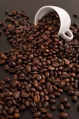 Fotobehang Koffiebar Grains de café sortant d'une tasse en gros plan