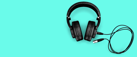 Modern headphones on a pale turquoise background with a long cable 3d render