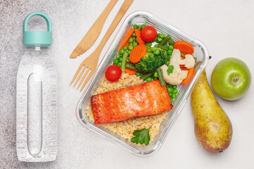 Salmon fillets with bulgur and vegetables in the container. Diet nutrition. Top view
