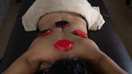 Brunette woman lying on a therapeutic stretcher with biomagnetism therapy magnets placed on her...