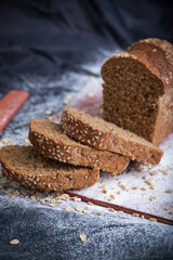 Black bread with sesame on a dark background in flour