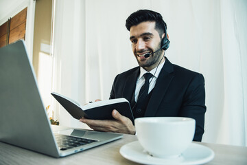 Thoughtful handsome call center businessman think of online project looking at laptop at workplace, positive professional consider solution sit at work desk in last weeken. Co-working space.