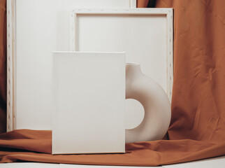 White blank canvases in an artistic interior with a mustard-colored cloth, near dried flowers in a clay vase