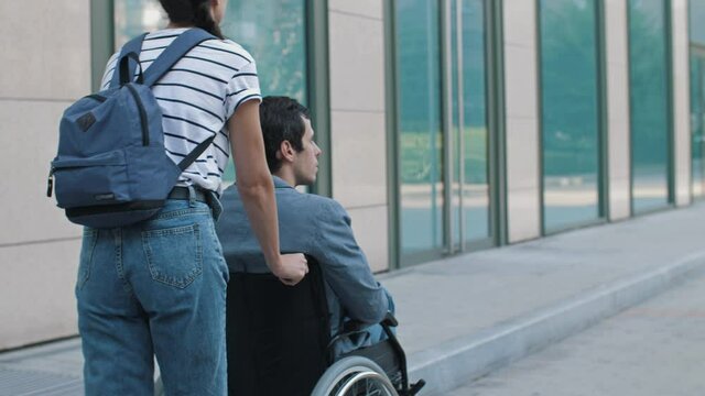 Woman walking with a disabled person in a wheelchair