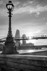 Czarno-białe pionowe ujęcie kładki dla pieszych Millenium Bridge w Londynie o zachodzie słońca - obrazy, fototapety, plakaty