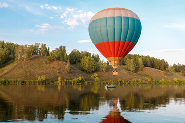 hot air balloon over the river, a boat is sailing along the river