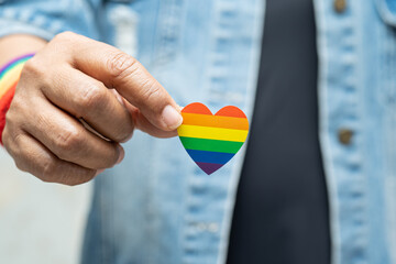 Asian lady holding rainbow color flag heart, symbol of LGBT pride month celebrate annual in June...