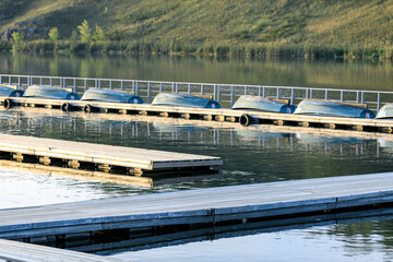 wooden pier installed on the water and boats lying in rows for rental and rent