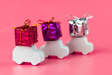 Gift delivery concept. Toy car delivers gift box on pink background. February 14 postcard, Valentine's Day, Christmas, New year, 
 March 8, international women's day. Minimalism style.