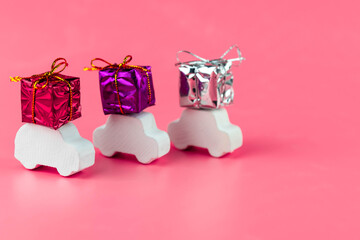 Gift delivery concept. Toy car delivers gift box on pink background. February 14 postcard, Valentine's Day, Christmas, New year, 
 March 8, international women's day. Minimalism style.