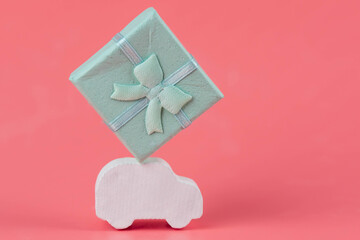 Gift delivery concept. Toy car delivers gift box on pink background. February 14 postcard, Valentine's Day, Christmas, New year, 
 March 8, international women's day. Minimalism style.
