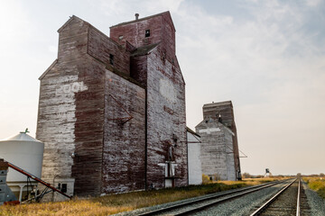 Fototapeta na wymiar Three red and white grain eleavotrs and trains. Waseca, Saskatchewan, Canada