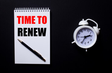 TIME TO RENEW is written in a white notepad near a white alarm clock on a black background.