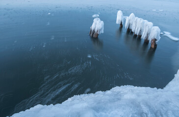 Ice breakwaters, covered with snow, stand in the winter sea. sea winter landscape background.