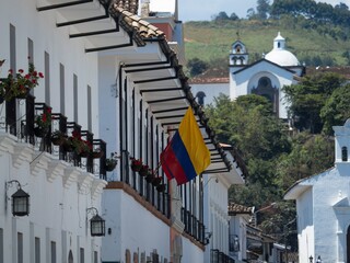Colombian national flag on white wall exterior facade colonial historic old building architecture...