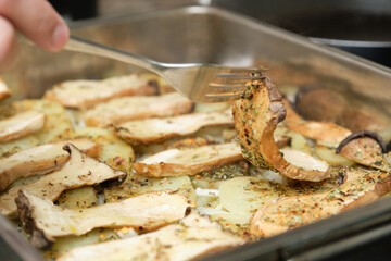 Fork turning around slices of king trumpet mushrooms (pleurotus eryngii) to cook them on the other side. Mediterranean diet.
