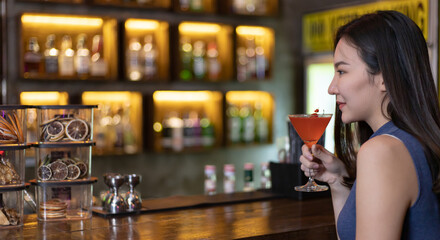 Young Asian woman with a sad face drinking cocktails in front of a vintage bar, Relaxing activities after work or hangouts, Place of entertainment for young adolescents or night club party.