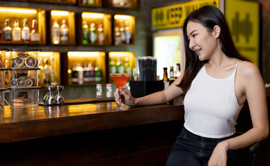 Asian alone women enjoy cocktails in front of a vintage bar, Relaxing activities after work or hangouts, Place of entertainment for young adolescents or night club party.