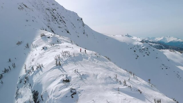 Aerial drone footage of skiers and snowboarders on Whistler mountain, BC, ski hill on a sunny day. 4K 24FPS.