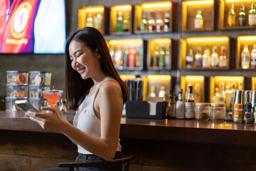 Asian alone women enjoy cocktails in front of a vintage bar, Relaxing activities after work or hangouts, Place of entertainment for young adolescents or night club party.
