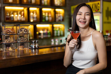 Asian alone women enjoy cocktails in front of a vintage bar, Relaxing activities after work or hangouts, Place of entertainment for young adolescents or night club party.