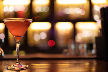 Strawberry juice mixed with alcohol soda in a cocktail glass in front of the vintage bar, Background image light bokeh light orange yellow.