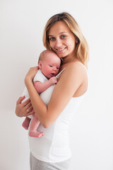 Pretty young smiling mother holding newborn baby