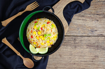Top view fried rice teas in spoon and fork on the black cloth on the old wood table. Right side copy space
