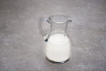 Glass pitcher half full with milk on a kitchen desk