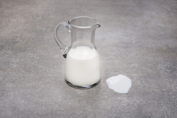 Glass pitcher half full with milk and spill