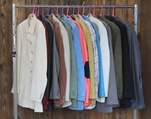 a set of colored business suit jackets on a hanger in a wardrobe
