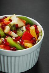 Fresh fruit salad cup made of juicy fruits on a black background.