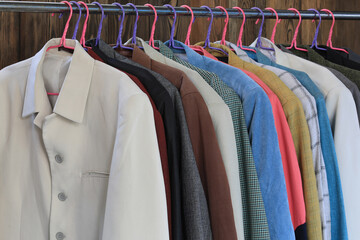 a set of colored business suit jackets on a hanger in a wardrobe