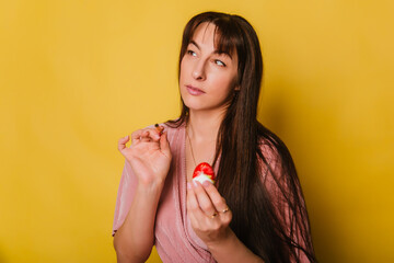 A woman in a pink dress paints eggs for the religious holiday of Easter.