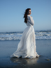 Fototapeta na wymiar romantic woman in full length sundress by the ocean blue sky beach