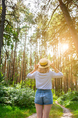 Hipster girl in straw hat standing in the forest. Wanderlust concept. Travelling ideas. Beautiful woman in the nature. Summer vibes.