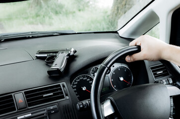 Theft of the car. Man with gun behind the wheel. Carjacking of vehicle. Robbing and crime.