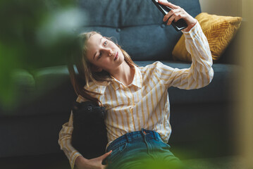 Tween girl with puppy making selfie.