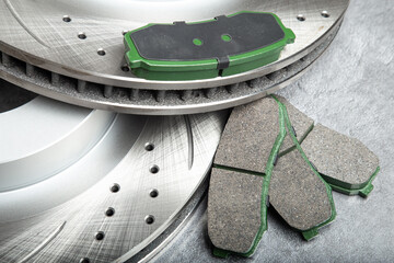 brake pads and perforated brake discs on a stone gray table